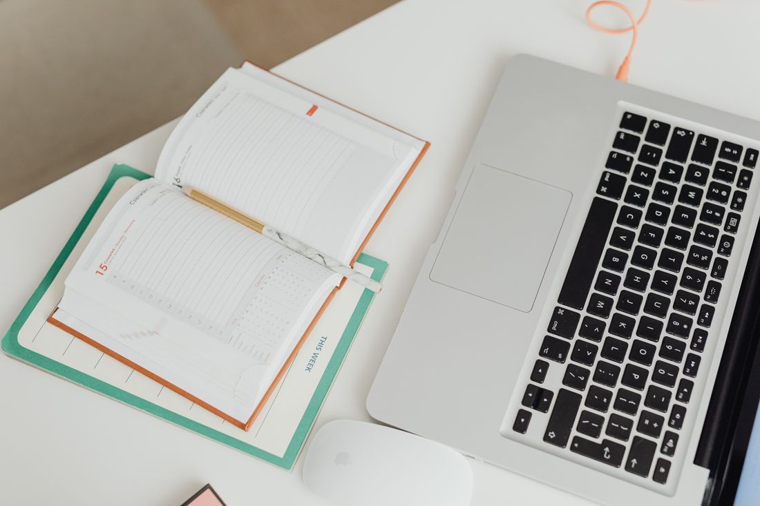 A planner and laptop on a desk, ready to set up a booking schedule